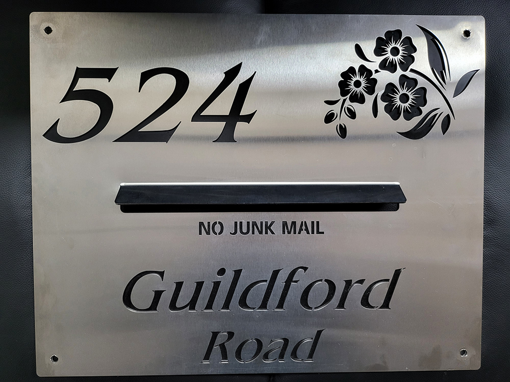 Custom stainless steel house number and address plaque with decorative floral engraving.